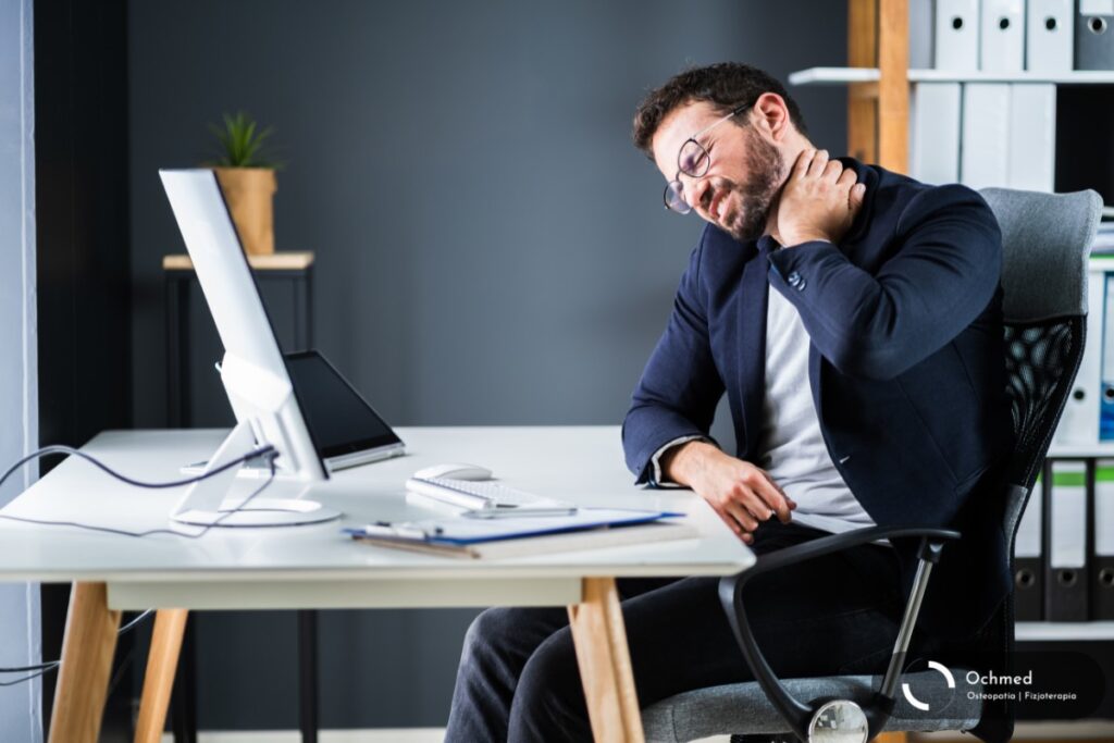 Mężczyzna z bólem szyi przy biurku. Stres a ból ciała