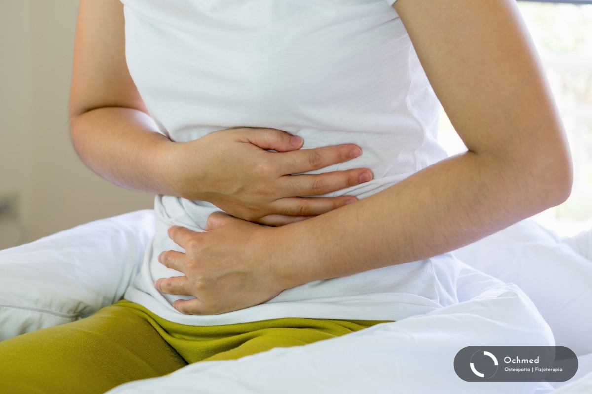 Kobieta trzyma się za bolący brzuch. Zespół jelita drażliwego (IBS) a napięcie mięśni brzucha